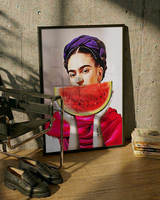 Framed Watermelon Frida - Dikhotomy artwork leaning on a wall beside a chair, shoes, and stacked books.