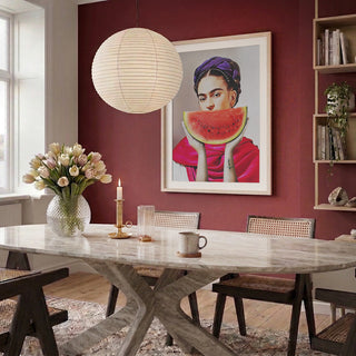 Dining room with a framed Watermelon Frida - Dikhotomy artwork on a red wall above the table.