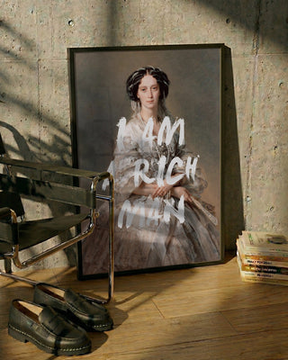Framed portrait of a woman in elegant attire with "I AM RICH MAN" text, leaning against a wall.
