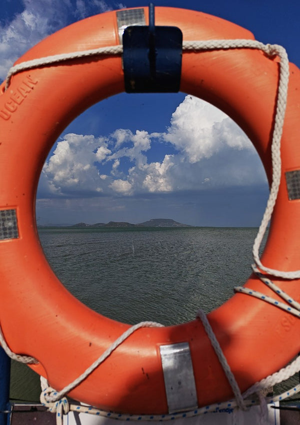 Three Layers of Presence by Bora Kőhalmi - an orange lifebuoy framing the green water and blue hills of Lake Balaton