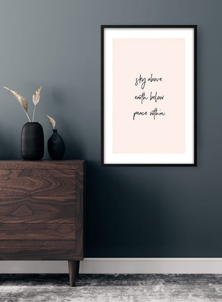 Framed Peace Within Plakat on a dark wall above a wooden dresser with vases and dried grasses.