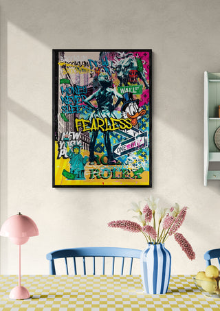 Colorful "Fearless" artwork by Ricardo Noble hangs on a wall above a dining table with flowers and pastel decor.