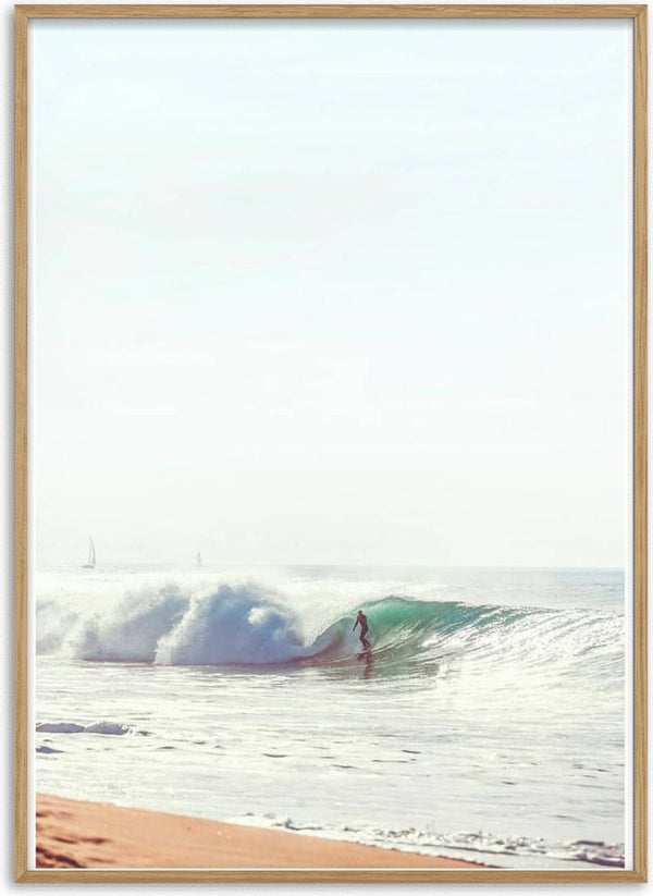 A surfer riding a wave close to the shore under a clear, bright sky.