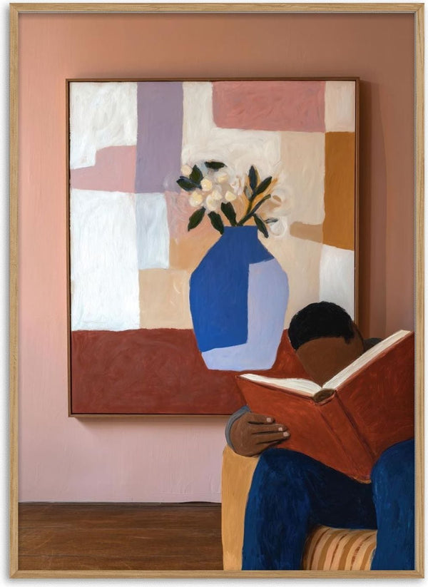 A person reading a large book sits in front of a colorful painting with a blue vase and flowers.